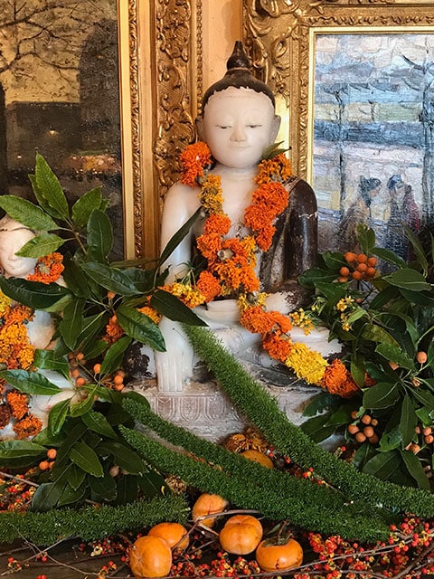 Adorned Buddhas with bittersweet, pomegranates, marigolds, ferns and berries.