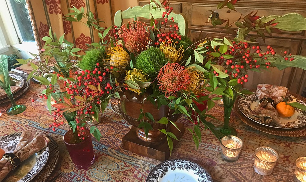 An unpredictable centerpiece - red berries, lime green carnations, and orange and yellow protea