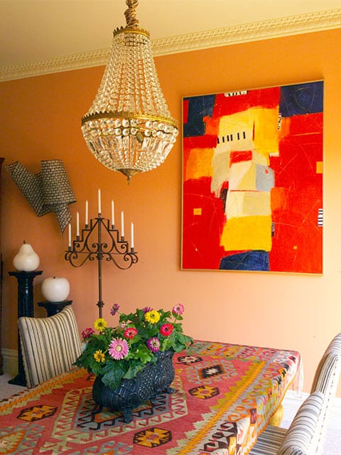 The bold abstract painting anchors the eclectic dining room