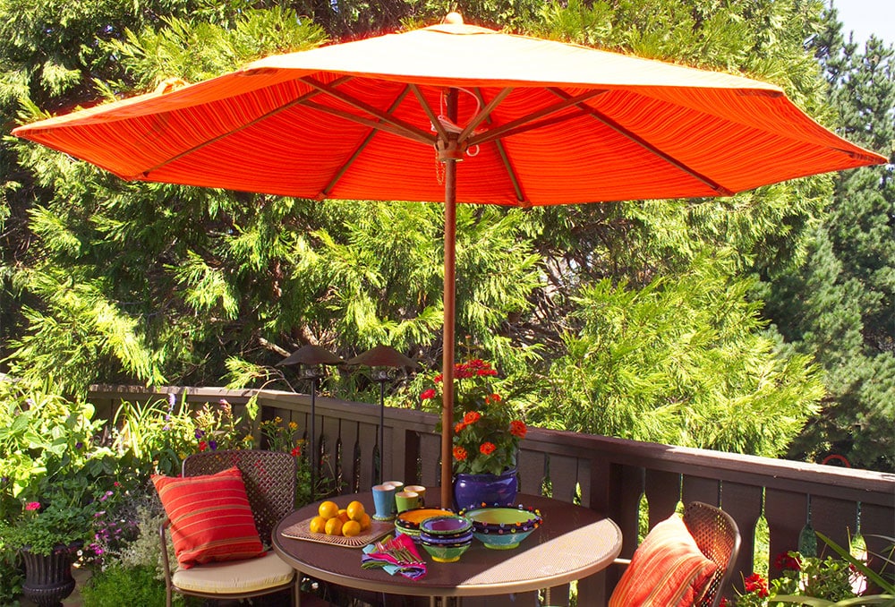 An orange umbrella and pillows bring the colorful feeling of the loft to the deck