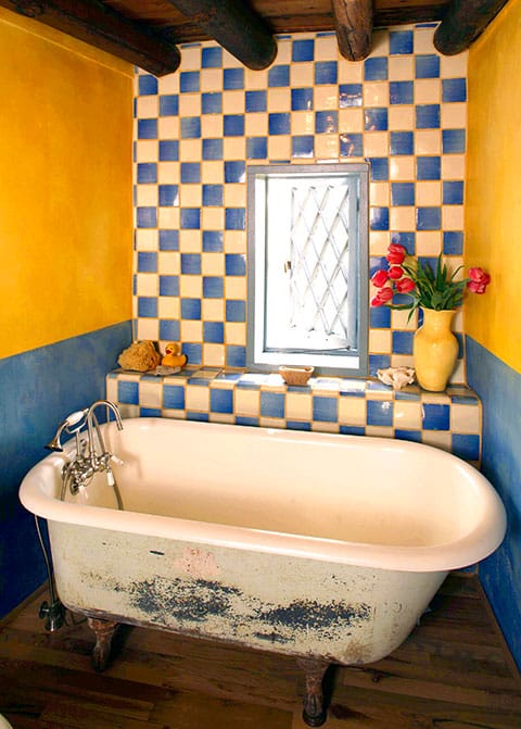A playful checkerboard wall perks up this old bathtub