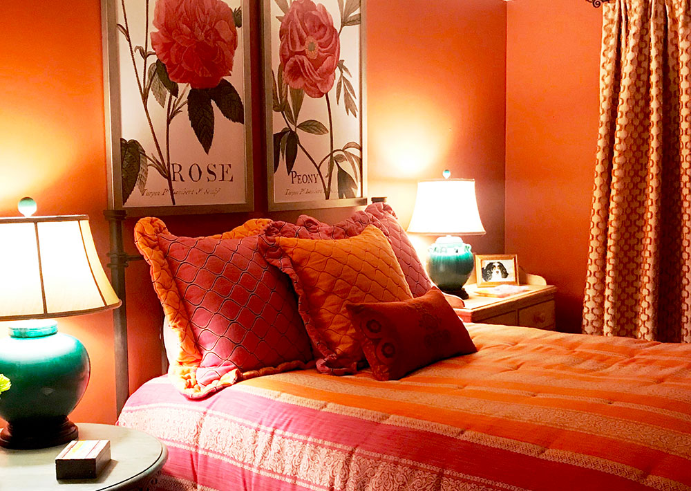 Pink and apricot bedding complements the terra-cotta walls.