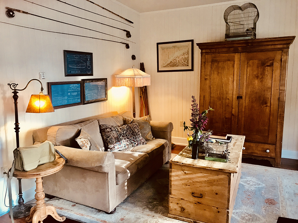 The sitting room displays brilliant blue boat building plans from the 1930s above the sofa