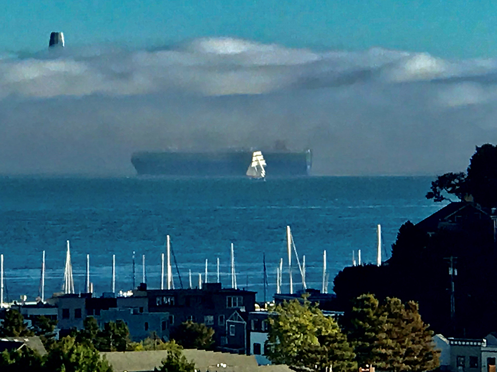 Linda Applewhite's photo for Mysterious black tanker passes white sailboat as Salesforce building pierces fog.