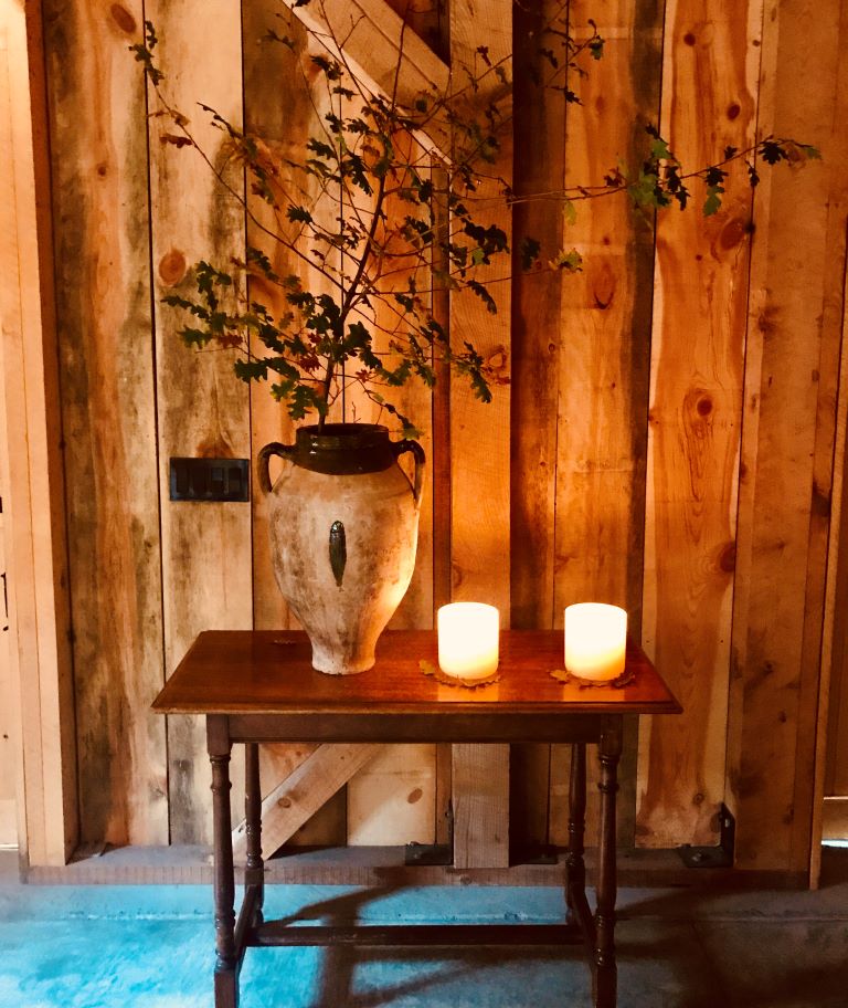 2 candles on side table in front of wood siding